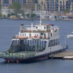 A ferry docked at Istanbul's bustling coastline with cityscape backdrop.