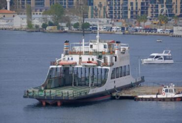 A ferry docked at Istanbul's bustling coastline with cityscape backdrop.