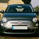 Classic Fiat 500 car parked on a residential street in the UK on a sunny day.