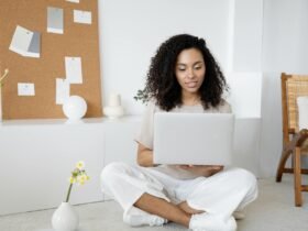 Young woman with curly hair working on her laptop in a cozy home setting, exuding confidence and focus.